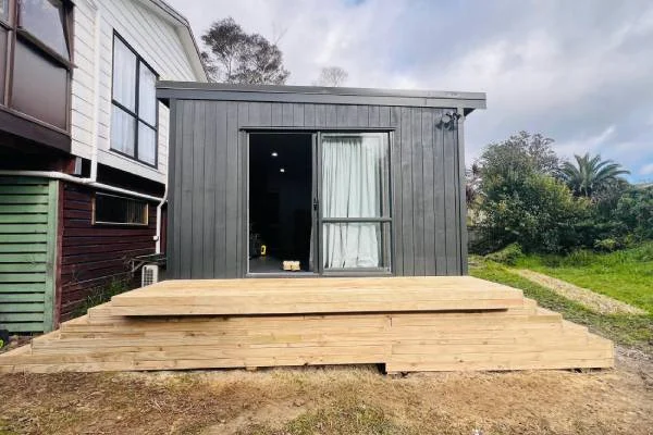 Small black cabin with wooden steps and sliding glass door